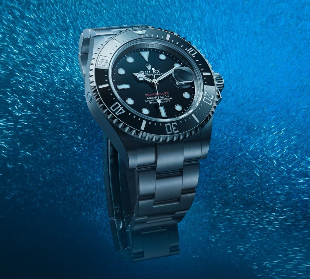A Rolex watch submerged in water with bubbles around it, highlighting its waterproof feature.