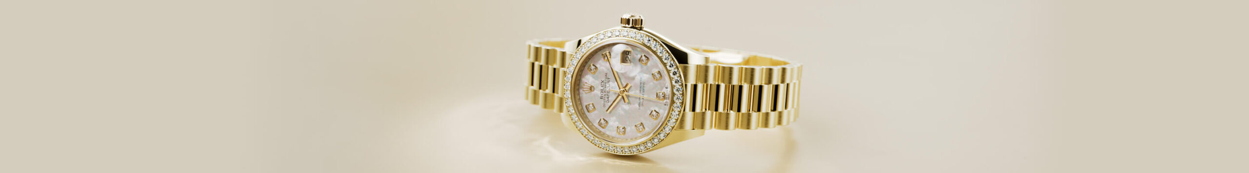 Gold wristwatch with a diamond-studded bezel and white dial, displayed on a beige background.